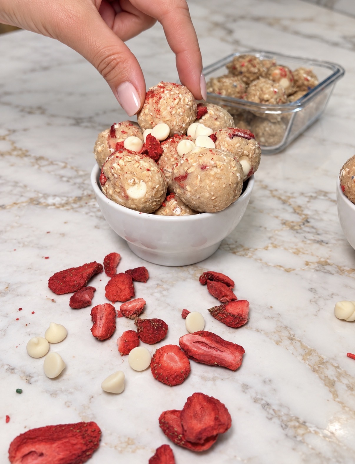 Strawberry Shortcake protein balls in a bowl with freeze-dried strawberries and white chocolate chips