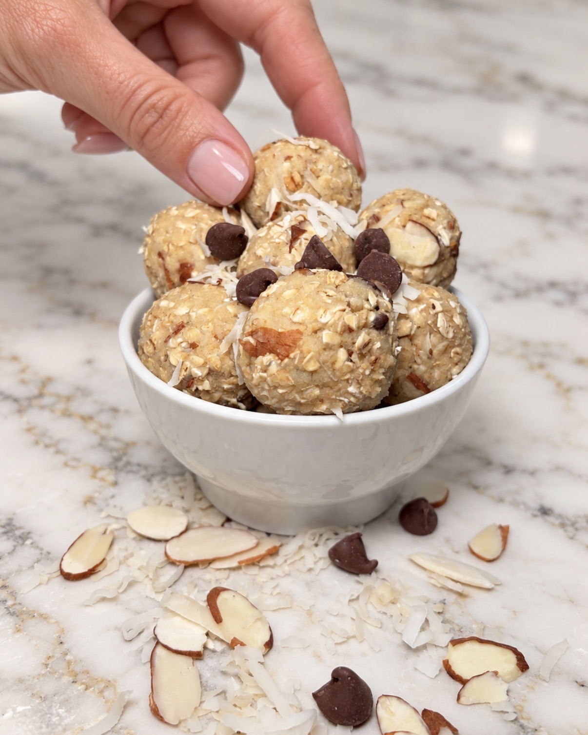 Choconut Almond Bliss protein balls in a bowl with coconut, almonds and chocolate chips